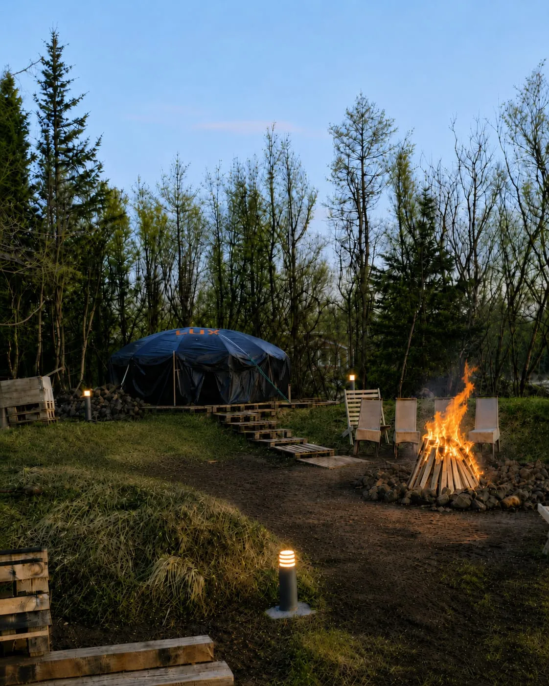 Sweat lodge at dusk, fire pit lit beside it